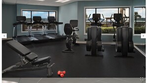 Ein Fitnessstudio mit Laufbändern, Crosstrainern und Gewichtecken.