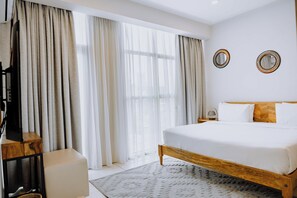 Ein Schlafzimmer mit einem Bett, Vorhängen, einem Fernseher und zwei Wandspiegeln.