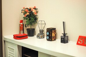 A white shelf with a red bag, a potted plant, a vintage camera, a small sculpture, and a black box. - Route 99 Hakone (Hakone)