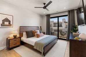 Une chambre à coucher moderne, avec un lit, une table de chevet, une lampe et un ventilateur de plafond.