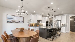 A modern kitchen with white cabinets, a central island with bar stools, pendant lighting, and a large island with a built-in oven.