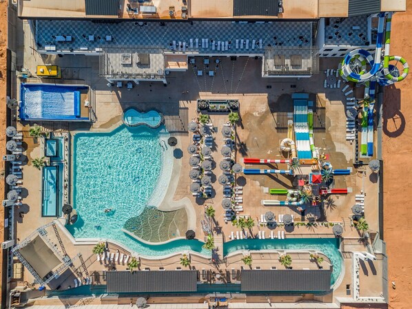 Vista aerea di un resort con diverse piscine, lettini prendisole e uno scivolo acquatico.