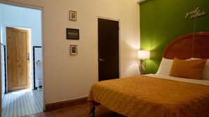 Habitación de hotel con una cama, una pared verde decorativa, una puerta de madera y una cita enmarcada en la pared.