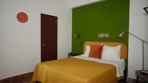 Una camera da letto con un letto, una sveglia, una porta e una parete verde.
