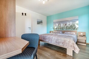 Une chambre à coucher comprenant un lit, un bureau, une chaise, une table de chevet et un tableau accroché au mur.