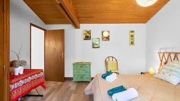 Une chambre à coucher avec un lit, une commode, une chaise et une table recouverte d’une nappe.
