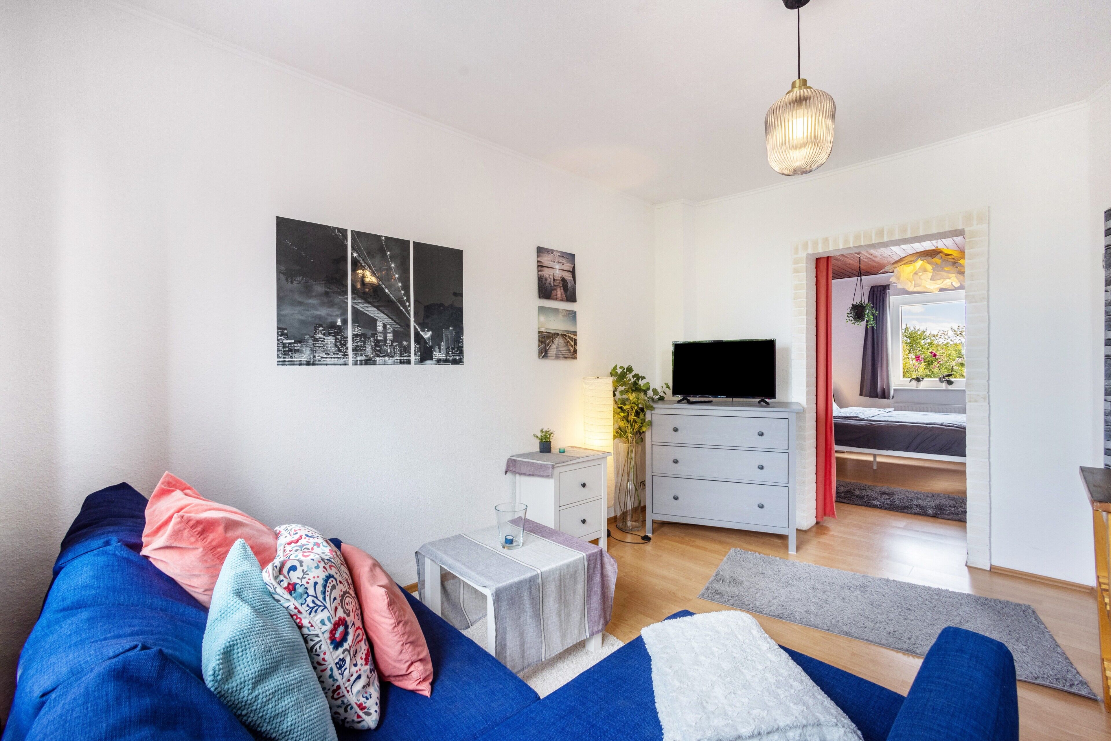 Una sala de estar moderna con un sofá, un televisor, una mesita y una ventana con vistas.