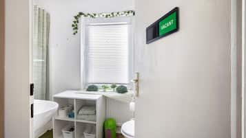 Un baño con bañera, inodoro y tocador con espejo.