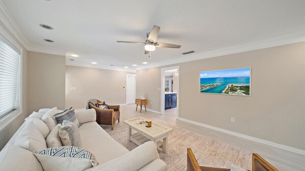 A spacious living room with a beige sofa, a coffee table, and a ceiling fan. - Gulf Tide Getaway 2 Bedroom Home (Bradenton)