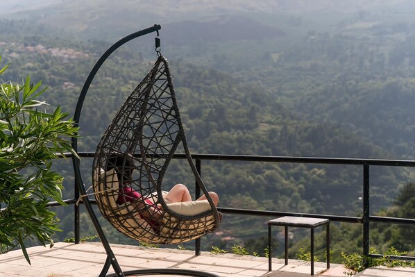 A hanging chair with a view of a mountainous landscape.