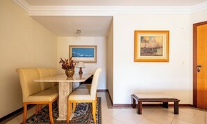 A dining area with a table, chairs, a vase with flowers, and two paintings on the wall. - Sea View Apartm. 130m From the Beach in BC Esa901 (Balneário Camboriú)