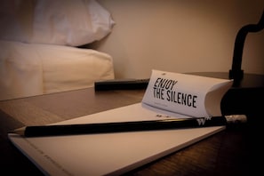 A notebook with a pencil and a card that reads "ENJOY THE SILENCE" on a wooden table.