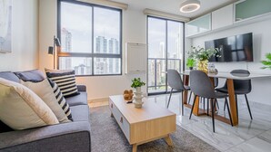 A modern living room with a sofa, coffee table, and dining area with chairs and a TV. - w Elegant 1BR w Bay View in Calle 50 (Panama City)