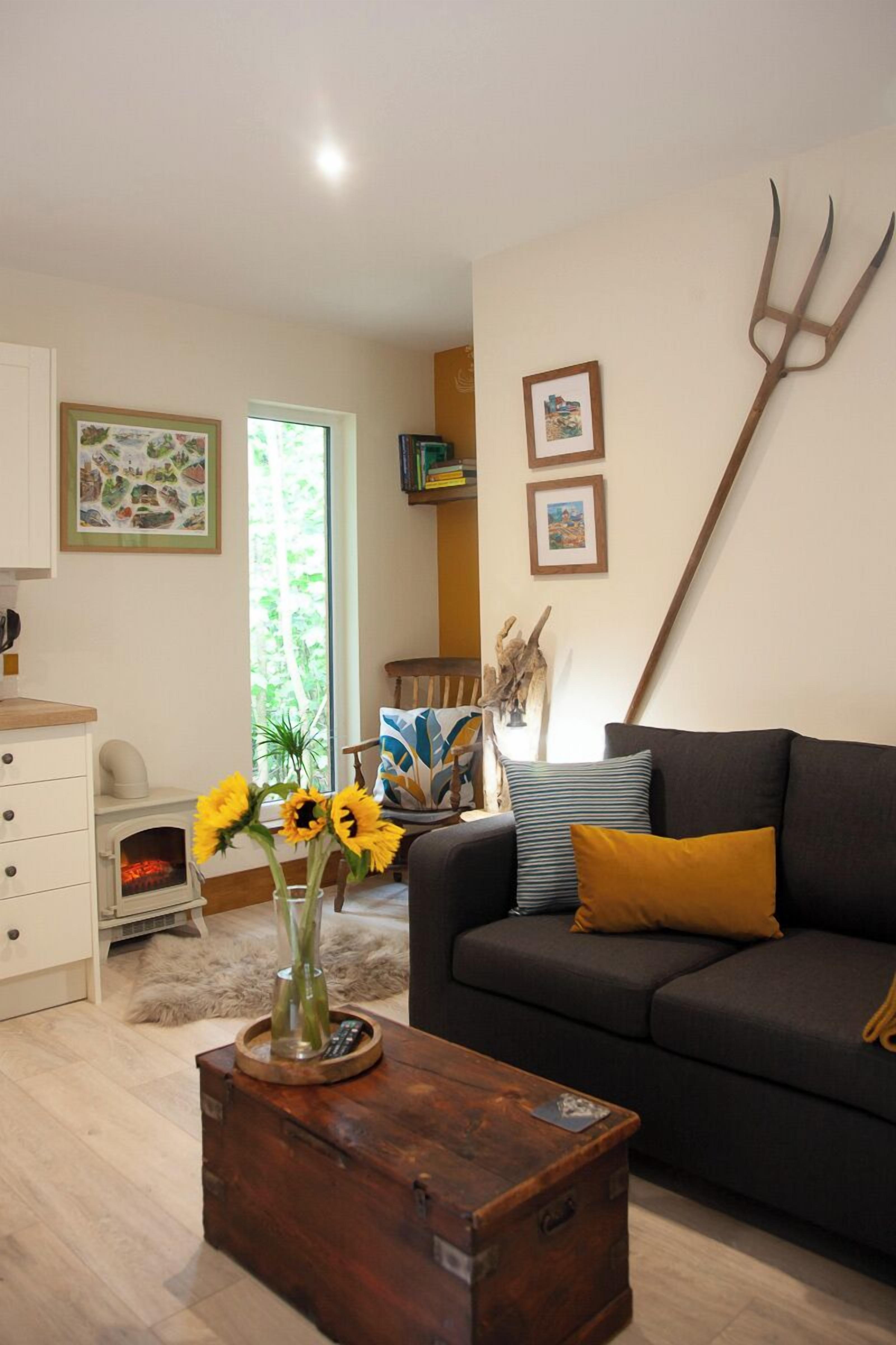 Una sala de estar con un sofá, una mesa de centro y un jarrón con girasoles.