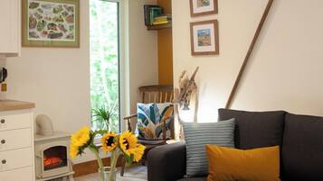 Una sala de estar con un sofá, una mesa de centro y un jarrón con girasoles.