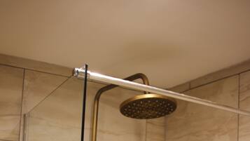 A shower with a handheld showerhead and a wall-mounted control panel.