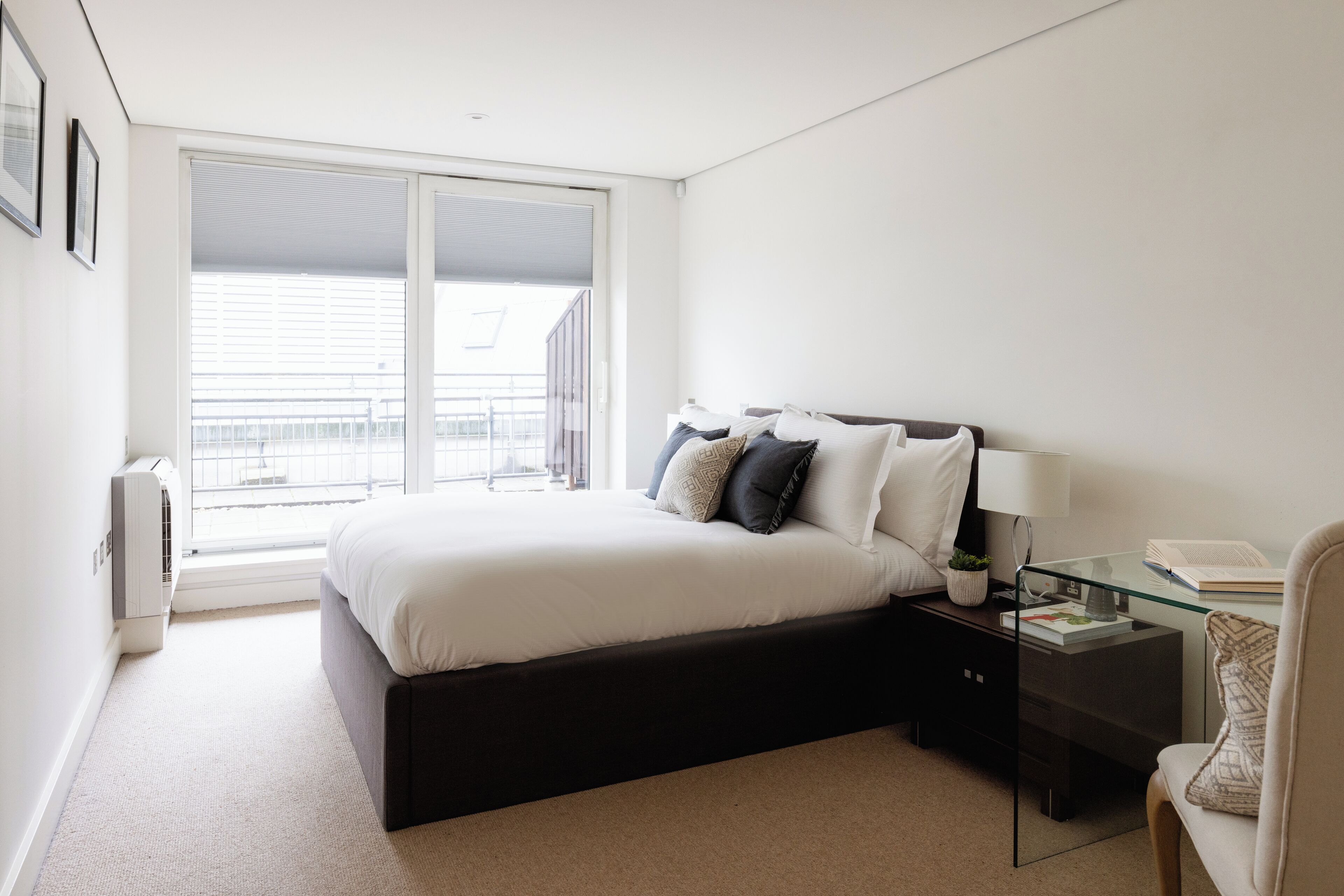 A bedroom with a bed, bedside table, lamp, and a chair.