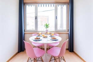 A dining area with a round table, pink chairs, and a window with curtains. - Guestready - Musichall (Porto)