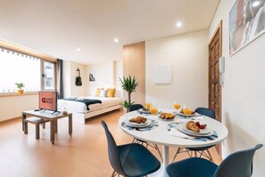 A modern hotel room with a dining area, a bed, a guitar, and a sign indicating guest readiness. - Guestready - Musichall (Porto)