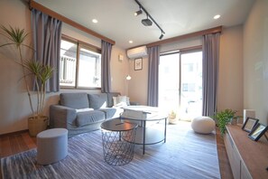 A modern living room with a sofa, a round coffee table, and a potted plant. - Route 99 Sengokuhara (Hakone)