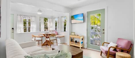 A bright living room with a sofa, a dining table, and a TV.