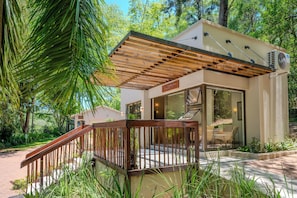 Un bâtiment moderne doté d’une terrasse en bois, d’un espace d’accueil et d’une porte vitrée donnant accès à l’intérieur.