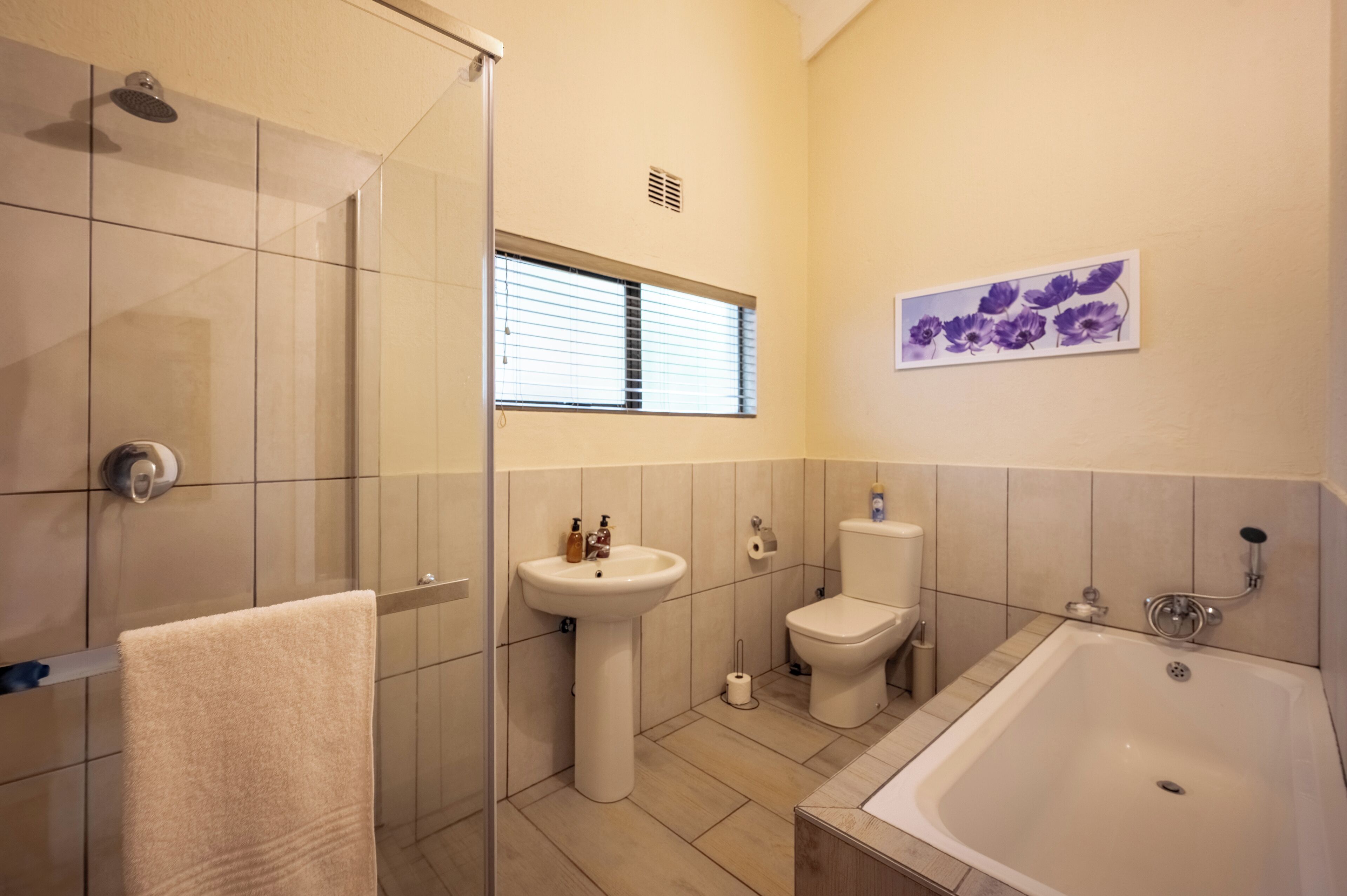 A modern bathroom with a shower, sink, toilet, and bathtub.