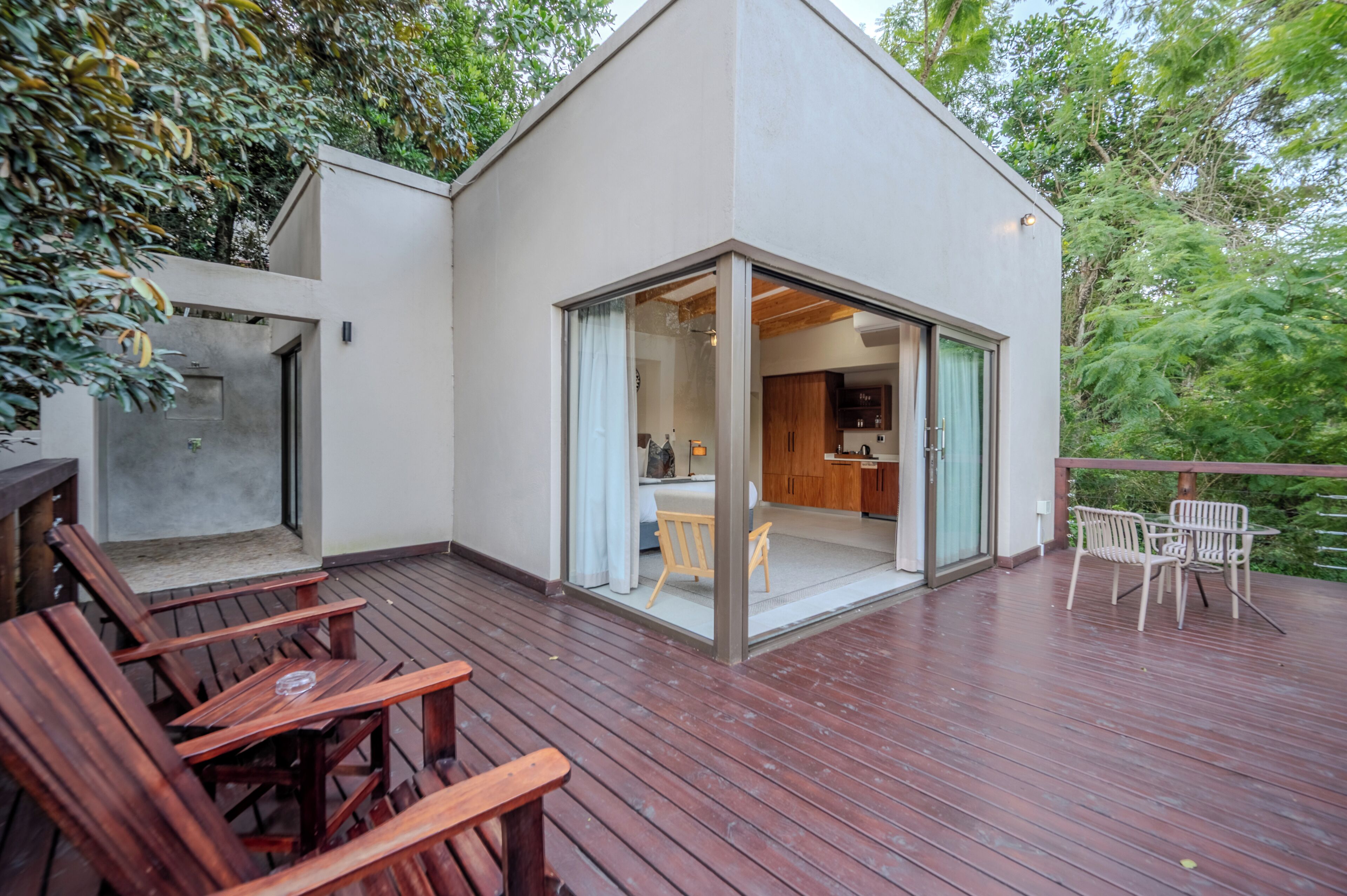 Una casa moderna con terraza, muebles de madera y una cocina visible a través de puertas de cristal.
