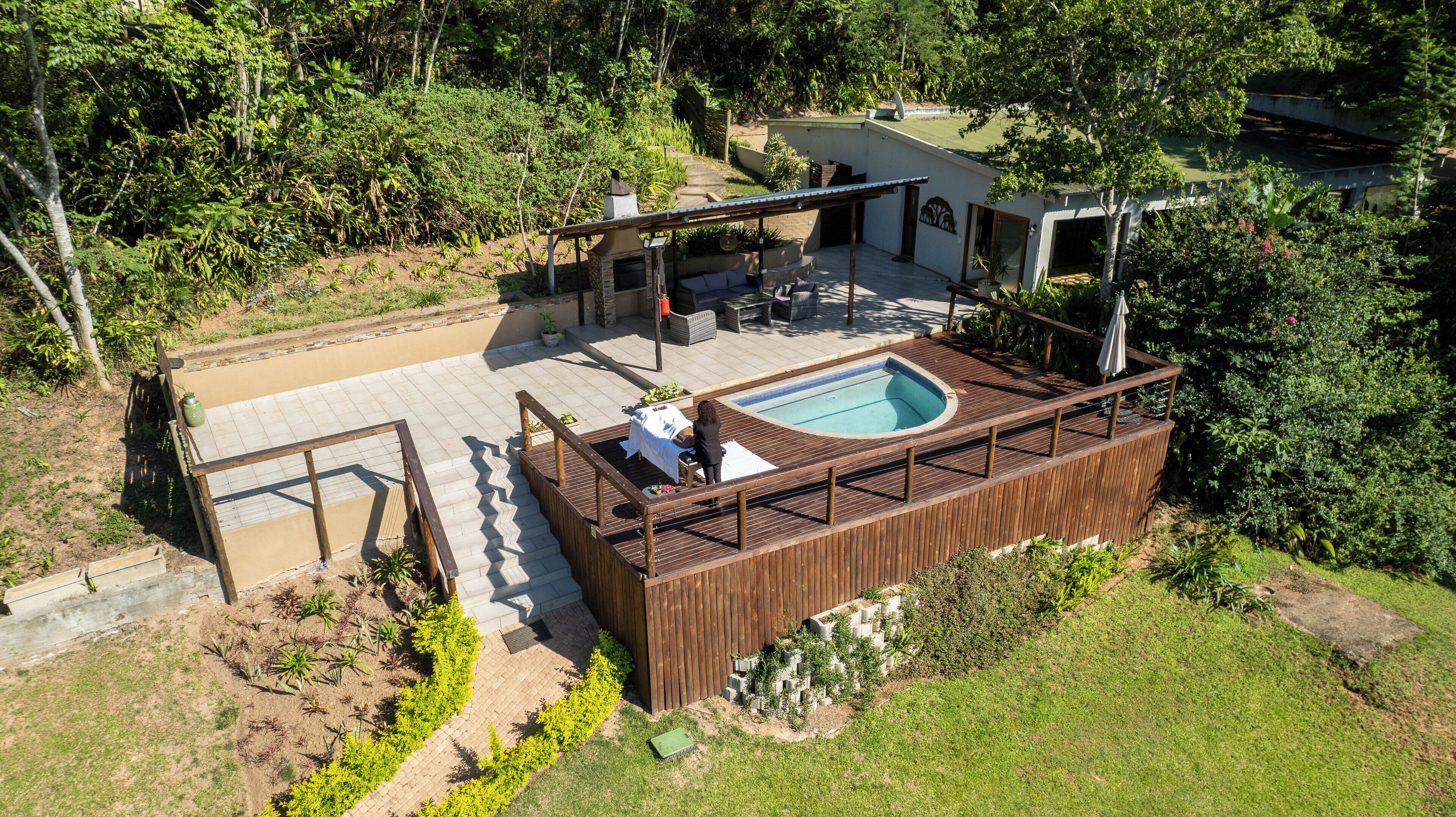 A rooftop pool area with a wooden deck, a hot tub, and a covered seating area.