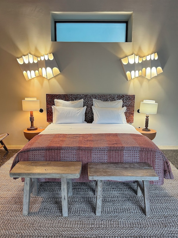 A hotel room with a large bed, two bedside lamps, a bench, and a small window. - Maison Émeraude (Ribeira Grande)