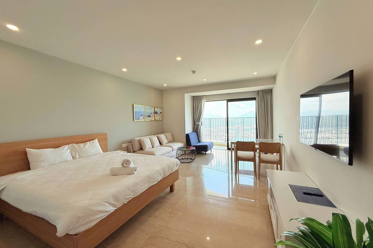 Una habitación de hotel con una cama grande, un sofá, una mesa de comedor y un televisor.