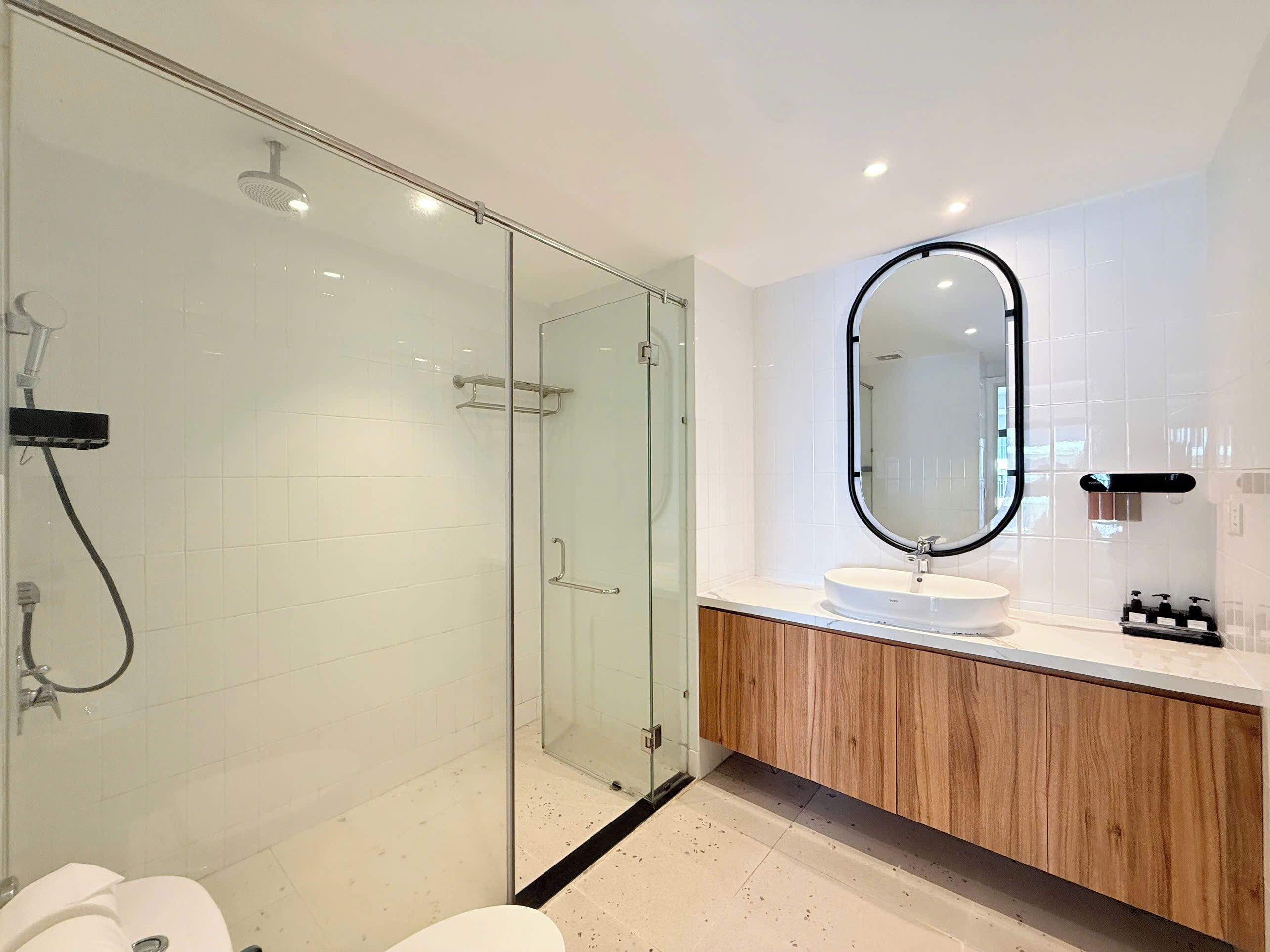 Une salle de bain moderne avec une douche à parois de verre, un meuble-lavabo en bois et un grand miroir.