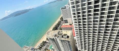 A high-rise hotel with a view of the ocean and a pool area.