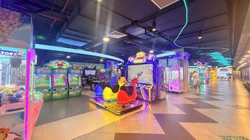 An indoor arcade with various gaming machines and a central area with a colorful horse statue.
