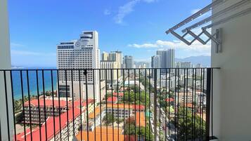 A balcony with a view of a cityscape, including high-rise buildings and a body of water.