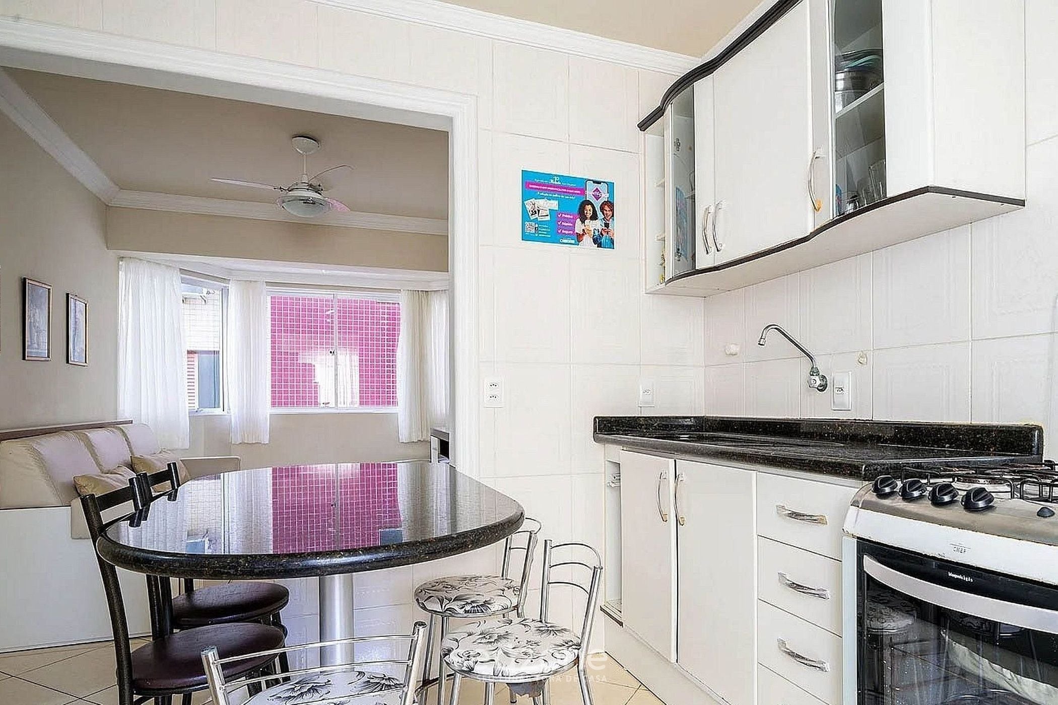A kitchen with a round dining table, chairs, a stove, and cabinets.