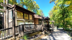 A lodge with a wooden deck, a stone fireplace, and a view of the surrounding forest.