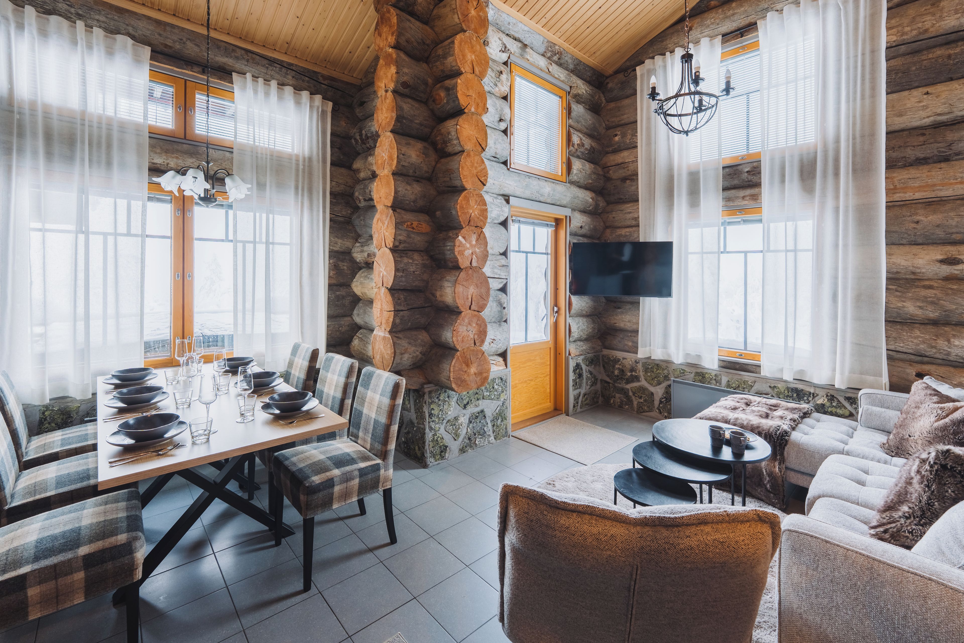 A log cabin interior with a dining area, seating, and a television.
