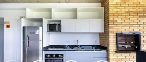 Una cocina moderna con un refrigerador de acero inoxidable, un microondas empotrado, una estufa a gas y una pared de ladrillo.