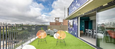 Terraza en la azotea con césped artificial, mobiliario de exterior y vistas a la ciudad.