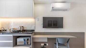 Una cocina moderna con estufa integrada, cafetera y televisor de pantalla plana montado en la pared.