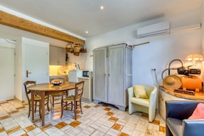 A compact kitchen with a dining table, chairs, a microwave, and a cabinet. - 'Petite Suite Douillette' Guest Room with Balcony, Wi-Fi, and Air Conditioning (Saint-Pargoire)