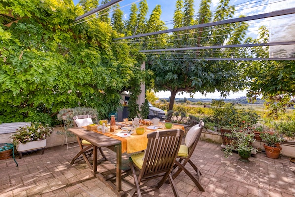 An outdoor patio with a table set for dining, surrounded by potted plants and trees. - 'Petite Suite Douillette' Guest Room with Balcony, Wi-Fi, and Air Conditioning (Saint-Pargoire)