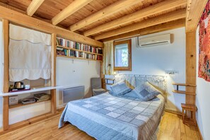 A cozy bedroom with a wooden ceiling, a bed with a quilt, a bookshelf, a radiator, and a window with curtains. - 'Petite Suite Douillette' Guest Room with Balcony, Wi-Fi, and Air Conditioning (Saint-Pargoire)