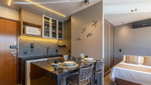 Een compacte hotelkamer met kitchenette, een eethoek en een bed.