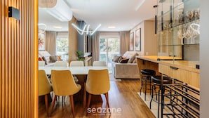 Een moderne woonkamer met een eethoek, een keuken met een glazen vitrinekast, en een bar.