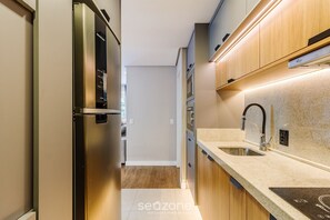 A modern kitchen with stainless steel appliances, wooden cabinets, and a granite countertop.