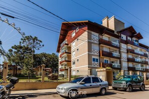 A multi-story residential building with balconies, a parked car, and a motorcycle.