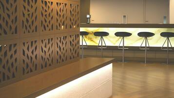 Un espace bar moderne avec un mur décoré de motifs, un comptoir éclairé et trois tabourets de bar.