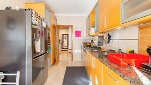 Una cocina moderna con electrodomésticos de acero inoxidable, encimera de granito y armarios amarillos.